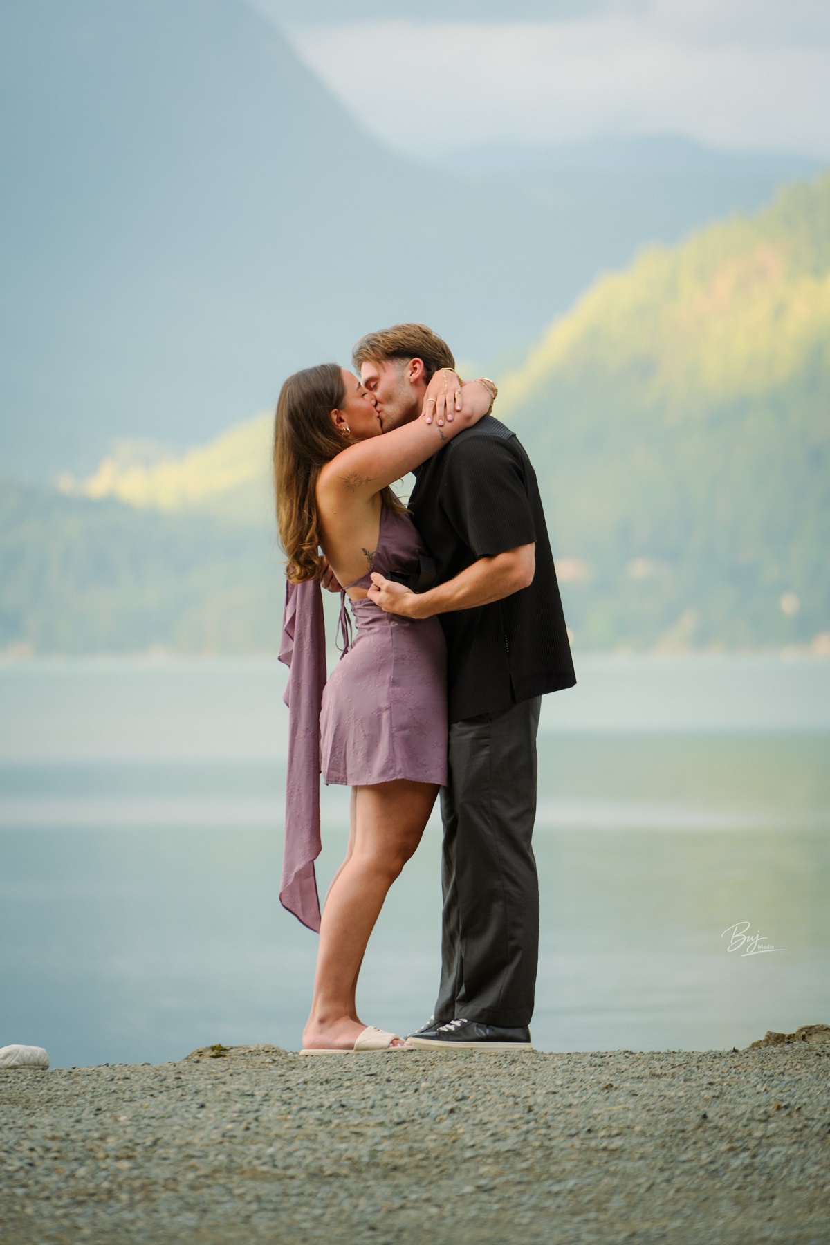 A couple kissing at the lakeshore, mountains behind